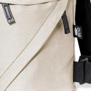 A messenger bag in a light beige colour with a black strap and branding tags. The material appears durable and textured.