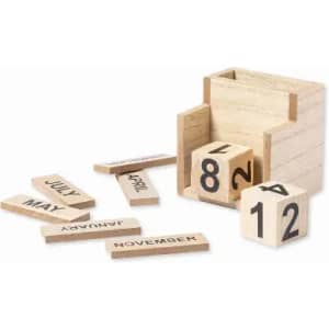 A wooden box containing numbered blocks and monthly name tiles in a natural finish. The blocks are scattered around the box.