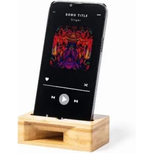 A phone stand made of natural wood holding a smartphone displaying a colourful music player interface.