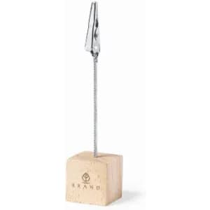 A cork clip holder with a metal clip attached to a thin wire, resting on a square cork base.