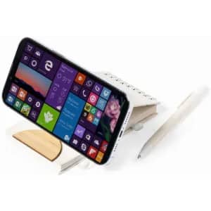 A phone holder made of wood displaying a smartphone, accompanied by a notebook and a pen.