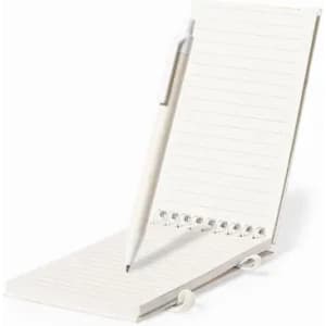 A notepad with lined pages and a silver pen attached, resting on a white surface. The notepad has a spiral binding.