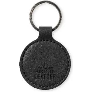A round black keychain made of leather, featuring a metal ring for attachment. The keychain has a logo embossed on it.