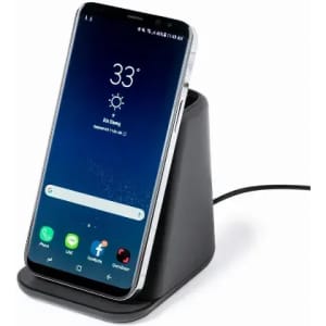 A phone charging dock in black with a smartphone resting in it, displaying the weather and time on the screen.