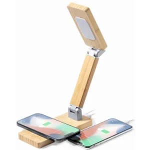 A wooden lamp with a flexible arm and a charging pad, positioned over two smartphones.