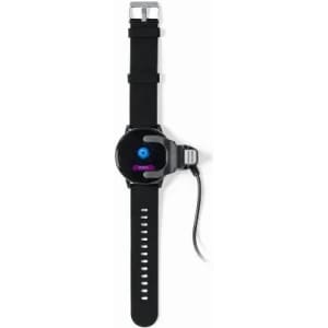 A smartwatch with a black strap and a round face, featuring a logo and a charging cable attached.