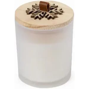 A candle in a frosted glass container with a wooden lid featuring a snowflake design.