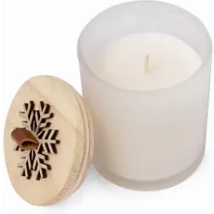 A white candle in a frosted glass container with a wooden lid featuring a snowflake design.