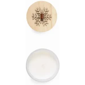 A wooden lid featuring a snowflake design covers a white candle in a clear container.