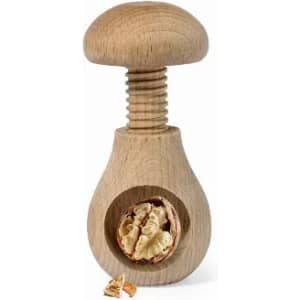 A wooden nut cracker featuring a mushroom-shaped top and a circular opening for cracking nuts.