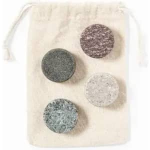 A drawstring pouch containing four round, textured stones in shades of grey, green, and brown.