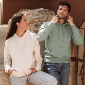 A casual hoodie in green worn by a man and a cream hoodie worn by a woman, both with a relaxed fit.