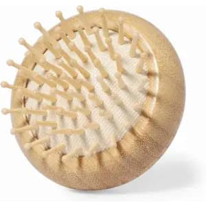 A hairbrush with a round, gold body and wooden pins, featuring a textured grip and a smooth base. It includes a logo.