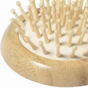 A wooden grooming board featuring multiple short pegs arranged in a circular pattern, set against a light background.