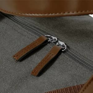 A grey fabric bag featuring brown leather accents and a double zipper with leather pulls.