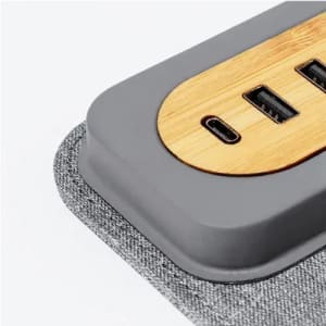 A power hub with a bamboo panel, featuring USB and USB-C ports, and a grey fabric base.
