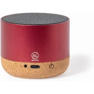 A portable speaker featuring a red metal upper and a natural cork base, with a logo and connection ports.