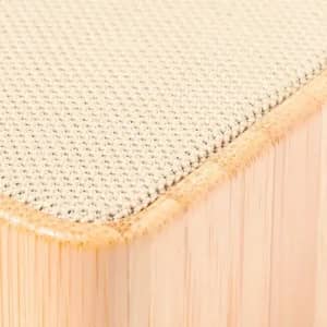 A close-up of a light beige textured surface with a rounded edge, featuring a natural bamboo-like base.