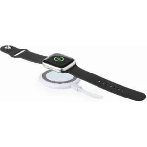 A smartwatch with a black strap placed on a round wireless charging pad. The pad has a white base.