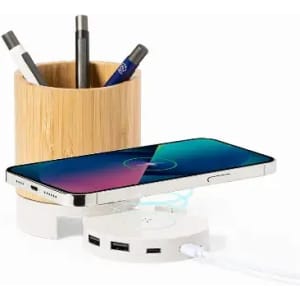 A desk organiser featuring a bamboo cup for pens and a white charging dock with a phone placed on it.