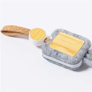 A grey felt product with a bamboo wood accent and cork strap, featuring a circular attachment.