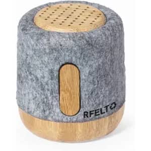 A cylindrical speaker with a grey felt exterior and a wooden base, featuring perforations on top for sound projection.