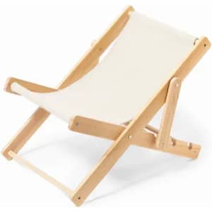 A deck chair with a natural wood frame and cream fabric seat, designed for relaxing outdoors.