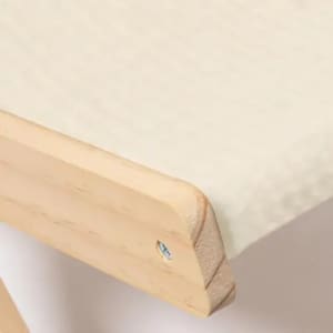 A close-up of a wooden edge with a smooth surface, featuring a light cream fabric underneath.