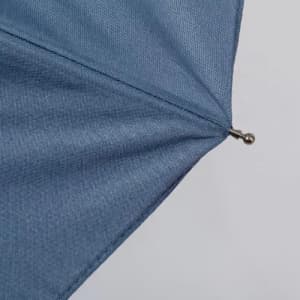 A blue umbrella with a pointed top and metallic closure is displayed. It features a textured fabric.