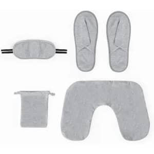 A grey travel set including a sleep mask, slippers, neck pillow, and pouch. All items feature a soft fabric texture.