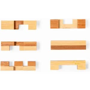A collection of wooden puzzle pieces in various shapes and shades of light and dark wood, arranged in two rows.