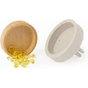 A wooden bowl containing yellow beads next to a grey concrete bowl with two prongs at the base.