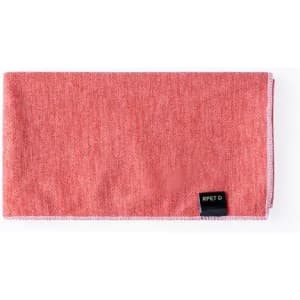A rectangular coral-coloured towel with a textured pattern and a small black label.