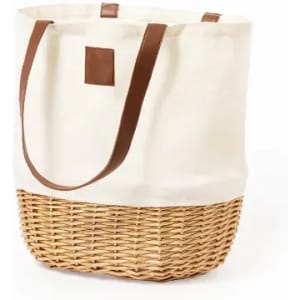 A tote bag with a cream canvas upper and woven, natural brown basket base, featuring brown leather handles.