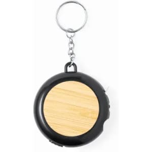 A keychain featuring a round black casing with a wooden circular insert. It includes a metal loop for attachment.