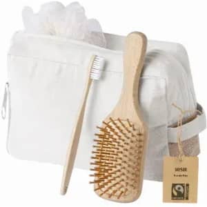 A toiletry bag with a bamboo hairbrush, toothbrush, and a tag. The bag is white, and the brush and toothbrush are light wood.