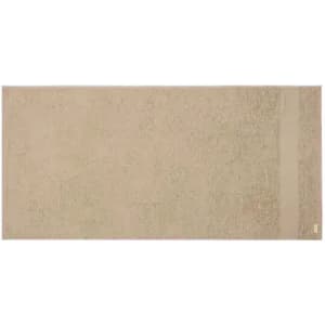 A bath towel in a soft beige hue, featuring a simple design and a small branding label on one side.
