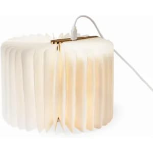 A lamp with a pleated white shade, featuring a warm glow and a grey cable for power.
