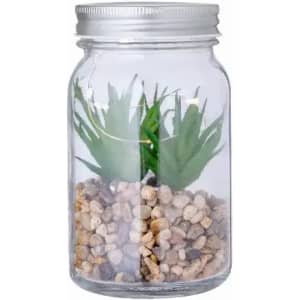 A glass jar containing artificial green plants and pebbles, featuring a metal lid.