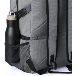 A drink bottle in a matte black finish, positioned in the side mesh pocket of a grey backpack.