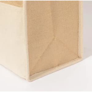 A storage basket made of natural jute material, featuring a simple, light beige colour. The basket has structured sides.