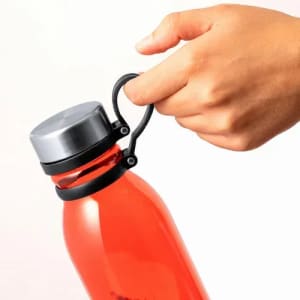 A drink bottle in vibrant red with a silver cap and a black handle, being held by a hand.