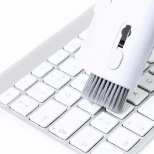 A cleaning brush with soft bristles in white, designed for use on a white keyboard.