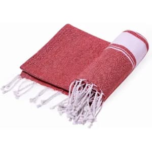 A red and white woven towel with tassels, folded to display its textured fabric.
