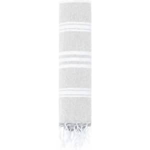 A towel in a light grey colour with white stripes and fringed edges, neatly rolled. It features a subtle texture.