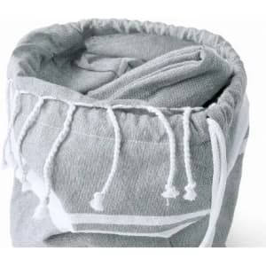 A grey towel with a drawstring closure, neatly rolled and featuring white tassels along the edges.