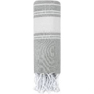 A rolled grey and white beach towel with fringed edges. The towel features alternating stripes.