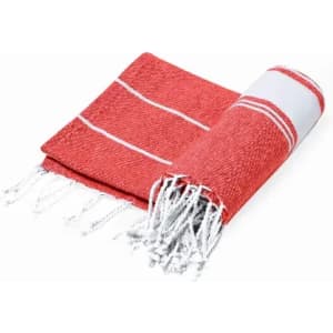 A red and white cotton towel with fringed edges, neatly rolled and partially unfolded. It features a striped pattern.
