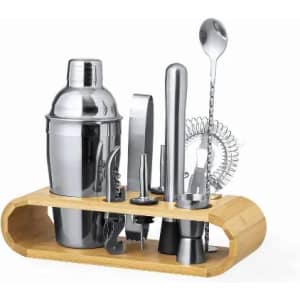 A cocktail shaker set with a polished silver finish, including various tools, displayed on a wooden stand.