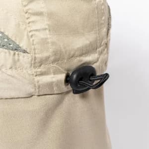 A beige hat with a decorative design and an adjustable cord. It features a fastening at the side for a snug fit.